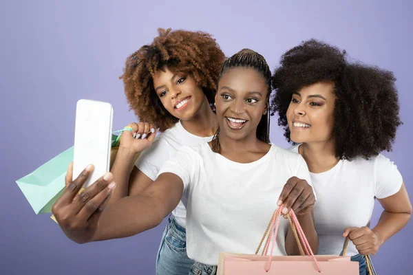 Eコマース 3つの楽しい黒女性ショッピングと楽しい作るセルフィーオン携帯電話 ポージング保持紙ショッパーバッグ以上パープル背景 ファッションとスタイルのコンセプト スタジオショット — ストック写真