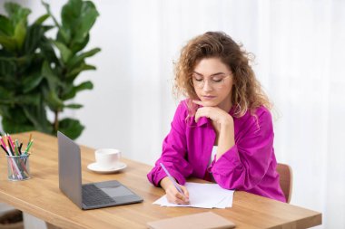 İçişleri Bakanlığı 'nda dizüstü bilgisayarla çalışan ve not alan serbest çalışan genç girişimci masa başında oturan, kağıt yazan, kontrol listesi hazırlayan, iş planlama, yakın çekim planlayan,