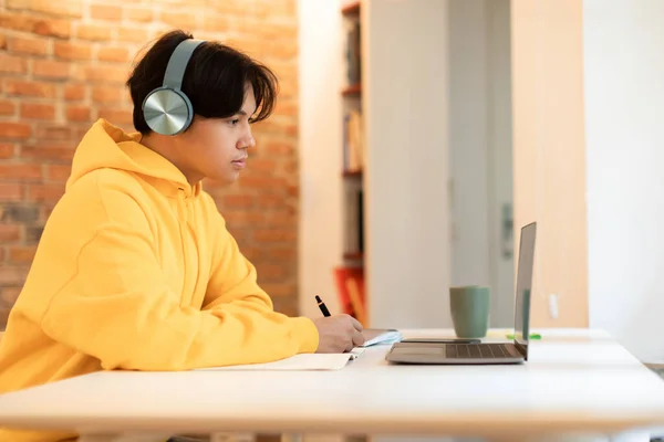 Серьезный Японский Подросток Проводит Видеоконференцию Ноутбуке Учителем Наушниках Сидящих Дома — стоковое фото