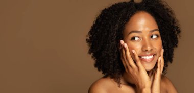 Deri bakımı rutin konseptinin artıları ve eksileri. Gülümseyen, yarı çıplak siyahi bir kadın yüzüne dokunuyor, reklam için fotokopi alanına bakıyor, kahverengi stüdyo arka planında izole edilmiş, web-afişi.