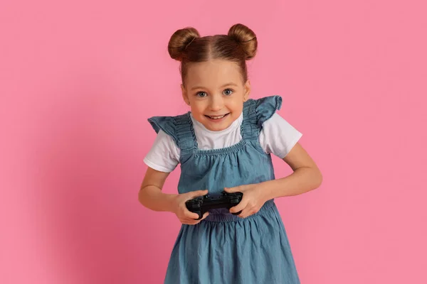 Pembe Stüdyo Arkaplanı Nda Dururken Oyun Oynayan Heyecanlı Küçük Kız — Stok fotoğraf