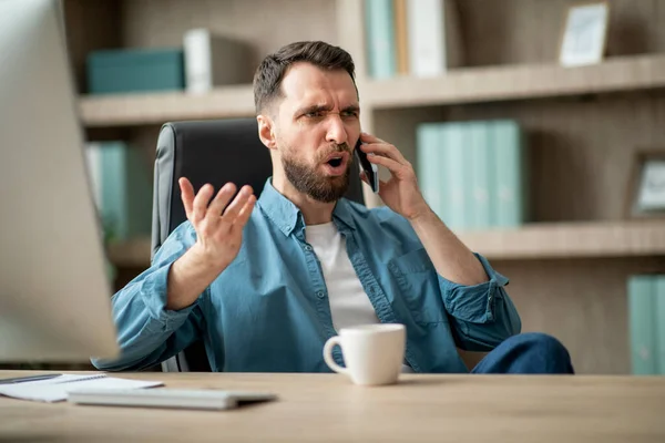 Θυμωμένος Νεαρός Επιχειρηματίας Μιλώντας Στο Κινητό Τηλέφωνο Στο Χώρο Εργασίας — Φωτογραφία Αρχείου