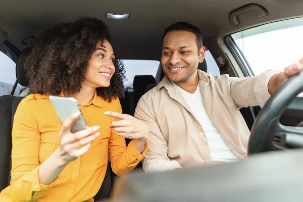 カーナビゲーションアプリ ドライバーの男に携帯電話でGpsアプリケーションを示す陽気な中東の女性は ガジェットで車を旅し ナビゲートします スマートフォンで自動車に乗るカップル — ストック写真