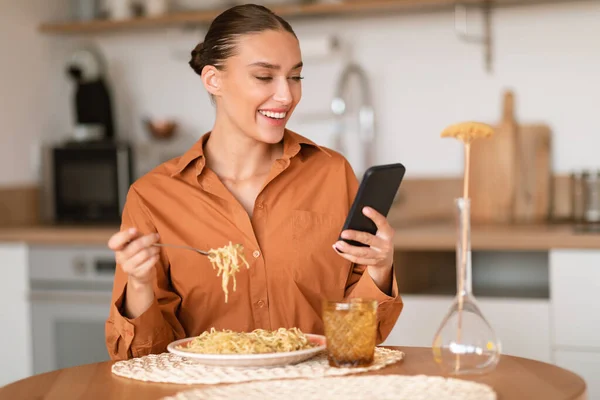 Szczęśliwa Europejka Korzystająca Smartfona Jedząca Makaron Domowej Roboty Podczas Lunchu — Zdjęcie stockowe