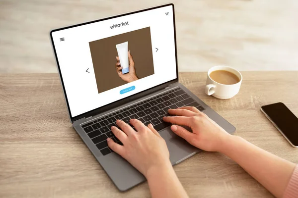 女士坐在桌旁 使用屏幕上装有奶油罐的现代笔记本电脑 女性购物狂喜欢订购化妆品 在网上购物 — 图库照片