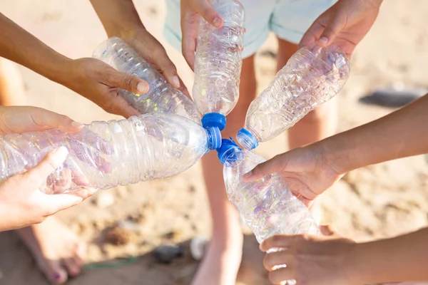 多种族青少年和年轻人的手拿着塑料瓶在海滩上的夏天 顶部视图 环境保护 循环利用 生态拯救和共同清理 团队合作 — 图库照片
