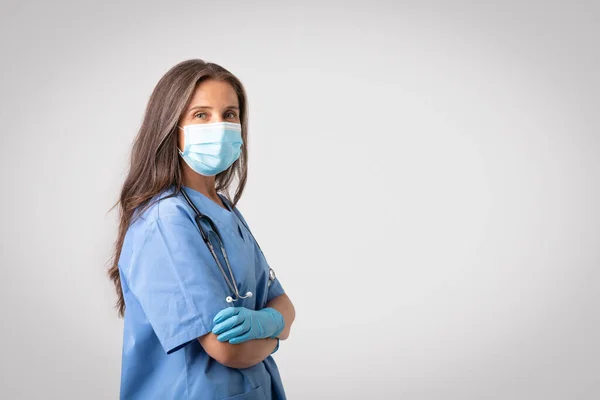 Professionelle Ärztin Mit Schutzmaske Posiert Mit Verschränkten Armen Und Blickt — Stockfoto