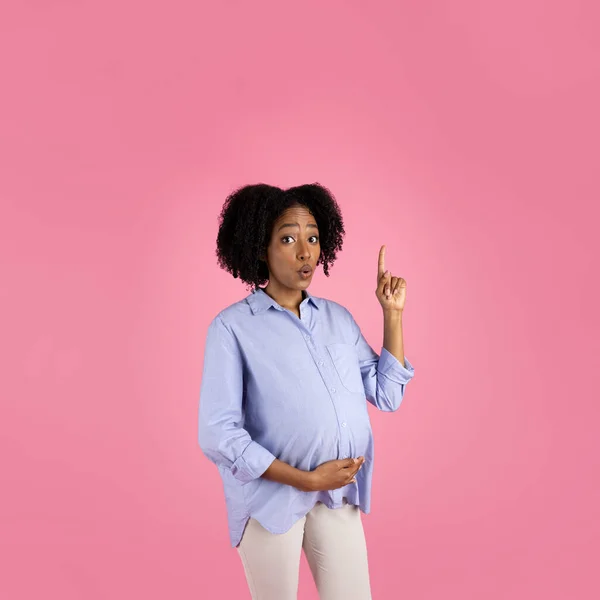 快乐的千年非洲裔美国卷曲孕妇 随意的大腹指 享受未来的母性 与粉红的工作室背景隔离 有想法 期待宝贝 创造解决方案 — 图库照片