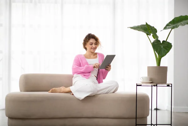 stock image Beautiful Smiling Woman Spending Time With Digital Tablet At Home, Reading News, Browsing Internet, Watching Videos, Checking Social Networks While Relaxing On Couch In Living Room, Copy Space