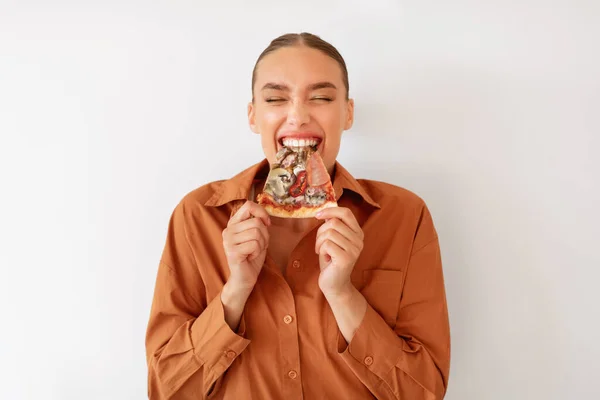 Nadšený Žena Těší Pizza Držení Kousání Chutný Plátek Stojící Bílém — Stock fotografie