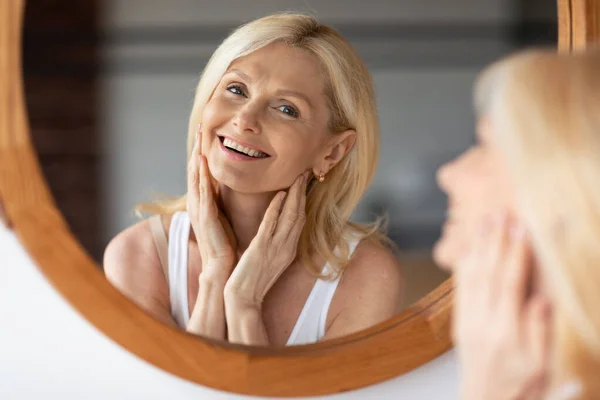 Hermosa Mujer Caucásica Envejecida Mirando Espejo Sonriendo Tocando Piel Suave — Foto de Stock