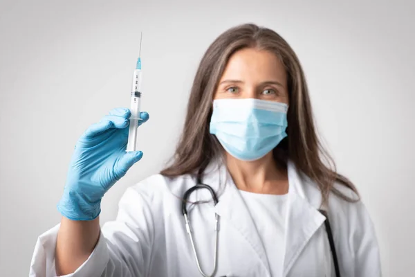 Serious Senior Woman Therapist White Coat Protective Mask Showing Syringe — Stock Photo, Image