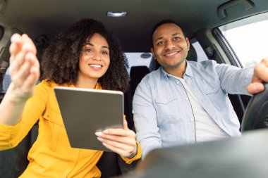 Çevrimiçi GPS Navigasyonu. Yeni arabalarını sürerken dijital tablet bilgisayar kullanan, gülümseyen kadın kısa yol hareketlerini eliyle gösteriyor. Otomobil gösterge panelinden göster