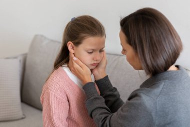 Ciddi bin yıllık Kafkasyalı kadın oturma odasının içinde üzgün genç kızını sakinleştiriyor. Aşk, ilişkiler, aile desteği ve bakımı, evde iletişim, sorunlara yardım