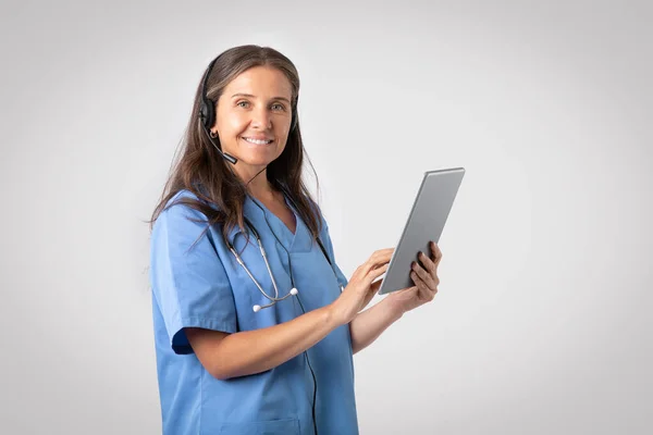 Friendly European Senior Woman Doctor Uniform Stethoscope Headphones Holding Tablet — Stock Photo, Image