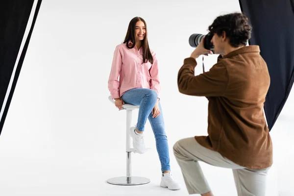 时尚的摄影 男式时装摄影师 为身着休闲装的年轻欧洲女人拍照 在现代演播室拍摄白色背景的照片 — 图库照片