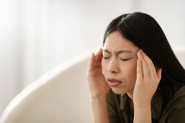 Chorą Młodą Azjatkę Siedzącą Kanapie Zamkniętymi Oczami Dotykającą Głowy Wnętrza — Zdjęcie stockowe