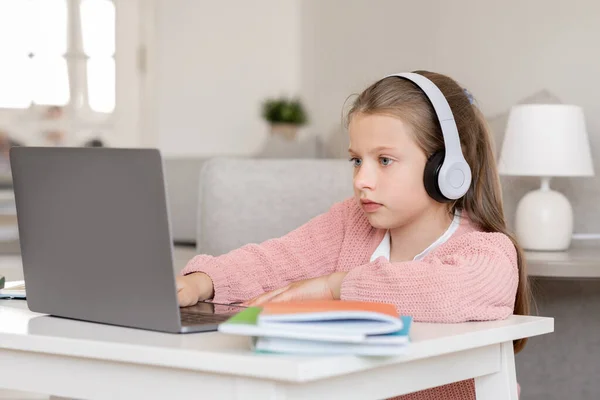 认真的千年期白人少女在耳机学习 做作业 在客厅的电脑在线课上观看 视频通话 在家里远程教育 — 图库照片