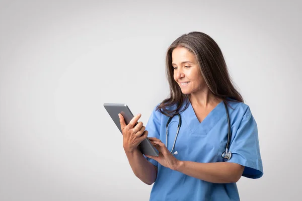 Happy Senior European Woman Doctor Blue Uniform Typing Digital Tablet — Stock Photo, Image