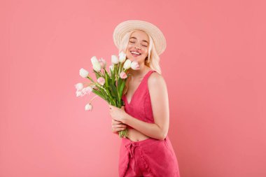 İlham verici sarışın kadın lale buketini seviyor, bahar tatilini kutluyor, pembe arka planda izole poz veriyor, stüdyo çekimi yapıyor. Hediye, doğum günü, tebrik, ilan ve teklif