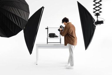Modern online mağaza için çantaların içerik fotoğraflarını çeken profesyonel fotoğrafçı, çeşitli ekipmanlarla fotostudio 'da çalışıyor, tam boy, boş alan.