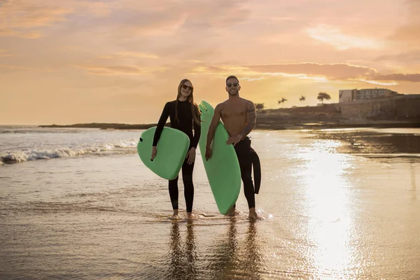 Młodzi Surferzy Para Deskami Surfingowymi Rękach Spacerujących Plaży Zachodzie Słońca — Zdjęcie stockowe