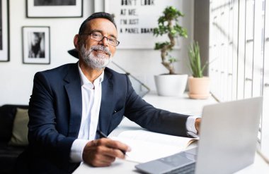 Takım elbiseli ve gözlüklü olgun Avrupalı bir adamın modern ofis içinde dizüstü bilgisayarda çalışmasından gurur duyuyorum. Başarı işi uzaktan, başlangıç projesi teknolojisi