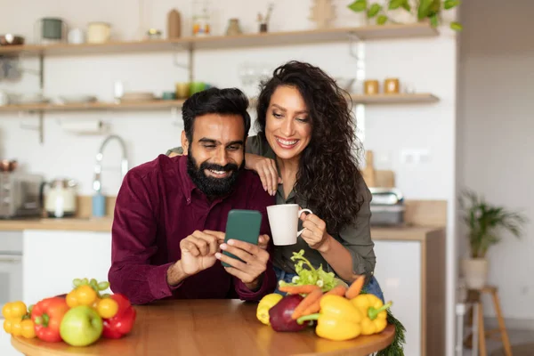Šťastný Středovýchodní Pár Pomocí Smartphone Spolu Posezení Kuchyni Interiéru Doma — Stock fotografie