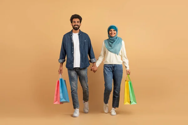 Porträtt Glada Muslimska Par Promenader Med Ljusa Shoppingväskor Över Beige — Stockfoto