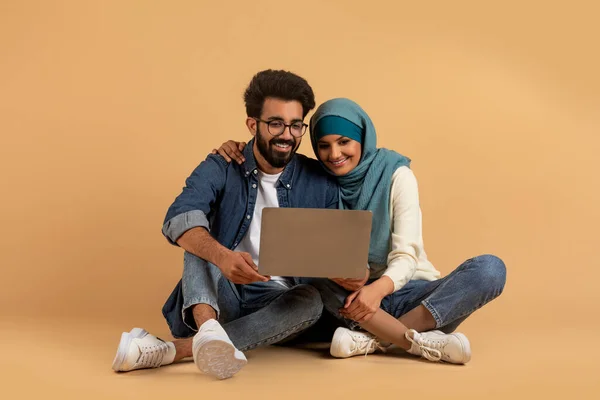 아라비 커플은 노트북을 사용하며 스튜디오에 있거나 Hijab 온라인 쇼핑을 하거나 — 스톡 사진