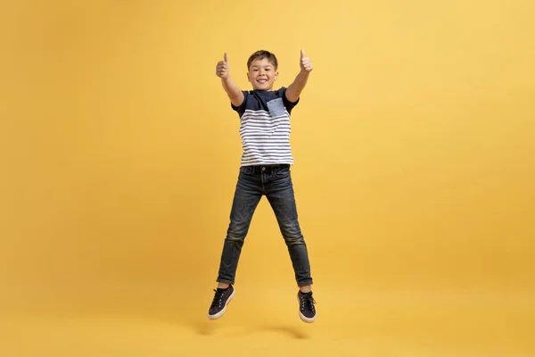 Симпатичный Веселый Мальчик Школьного Возраста Случайном Прыжке Воздух Показе Больших — стоковое фото
