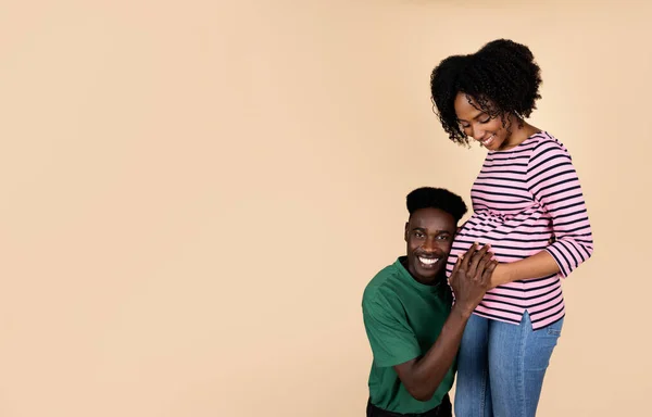 快乐的年轻非洲裔美国丈夫 带着怀孕妻子的大耳朵听着 被米色工作室背景隔离 一起等孩子 支持和关系 — 图库照片