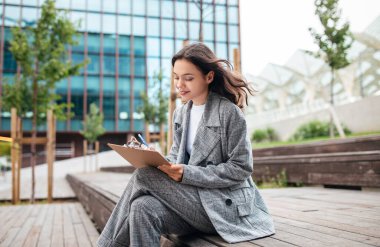 Şehir dışındaki Modern Ofis Binası 'nın yakınında CV CV CV CV yazıp, Evrakları ve Belgeleri Okurken Mutlu İş Kadınları. Şehirdeki Belgelerle Çalışan Girişimci