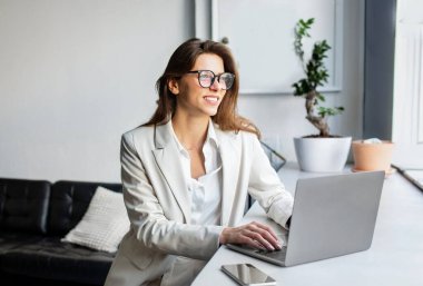 İnternet işi. Çevrimiçi Bilgisayarı kullanan, İçerde Gözlük Takan Mutlu Avrupalı Genç İş Kadını. Serbest Çalışan Kadın İçişleri Bakanlığı 'nda çalışıyor.