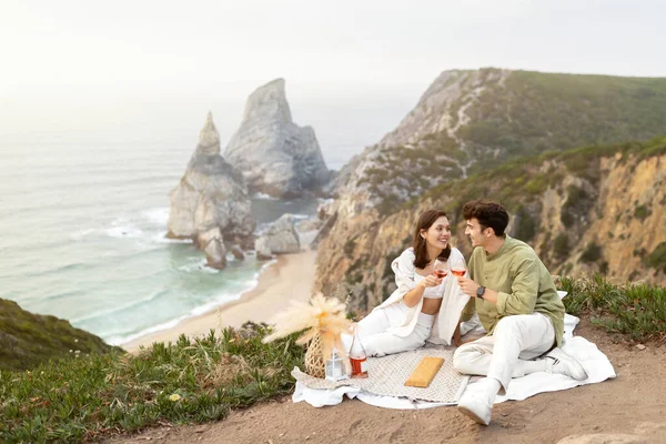 一对快乐的年轻夫妇在岩石上举行浪漫的野餐 在海滨的海岸线上 自由自在的空间里 有着令人叹为观止的景色 暑假和周年庆祝活动 — 图库照片