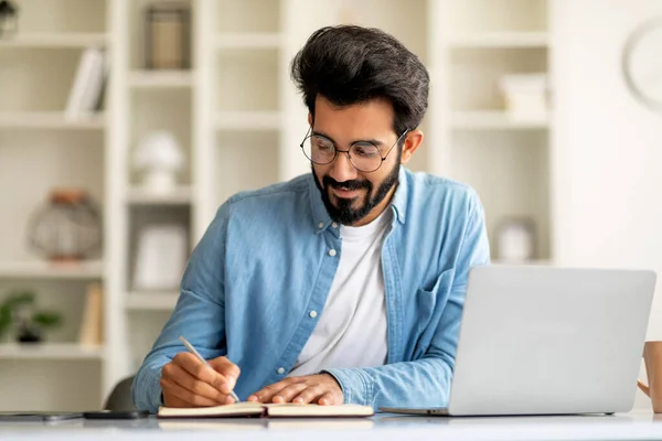 Smiling Indian Man Taking Notes While Working Laptop Computer Home — Stock Photo, Image