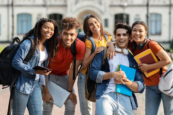 大学友谊的概念 快乐的多种族学生团体在户外放风 快乐的年轻文化朋友背着背包和工作手册在相机前拥抱和微笑 — 图库照片