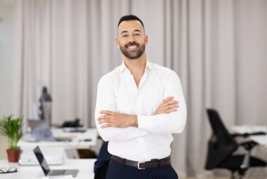 Beyaz gömlekli, sakallı, göğsünde kolları çapraz olan neşeli, kendine güveni tam, Avrupalı, çekici bir adam. Profesyonel meslek, başarılı iş, iş ve teklif