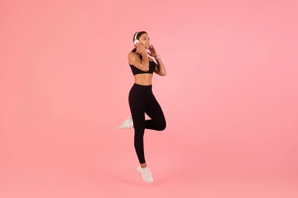 Portret Van Jonge Vrouw Sportkleding Draadloze Koptelefoon Springen Roze Achtergrond — Stockfoto