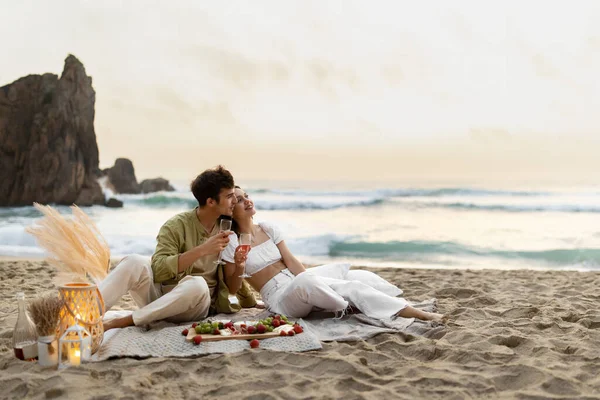 사랑하는 부부가 포옹하고 와인을 마시고 해변에서 피크닉 데이트를 즐기며 낭만적 — 스톡 사진