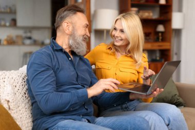 Avrupa kıdemli eşleri dizüstü bilgisayar kullanarak internetten film izliyor ve internette sörf yapıyor, hafta sonlarını birlikte evde koltuklarda oturarak geçiriyorlar. Bilgisayara bakan, interneti gezen mutlu emekli çift.