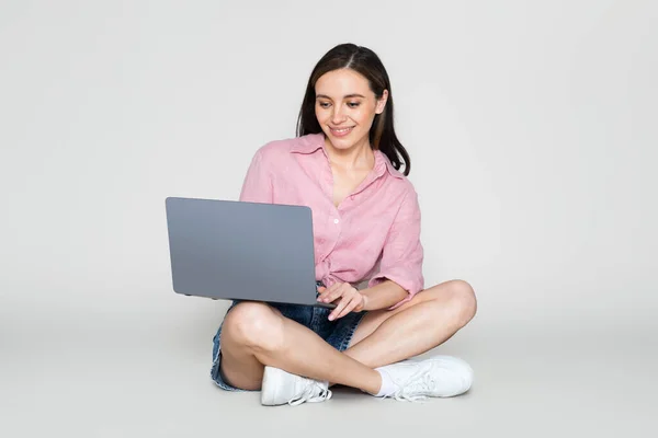 快乐漂亮的年轻女人穿着休闲的夏装坐在地板上 用电脑笔记本电脑 上网工作 找工作 与世隔绝的背景 — 图库照片