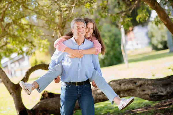 都会の公園を歩いている間に笑っている幸せな熟女カップルの肖像夏には 男はピギーバック彼の幸せな妻 コピースペース — ストック写真