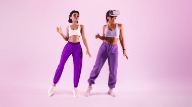 Meta evrende eğlenceli dans hareketleri. Sanal gerçeklikte 3 boyutlu avatar olarak dans eden spor gözlük takan mutlu Afro-Amerikan kadın, mor stüdyo arka planı, panorama