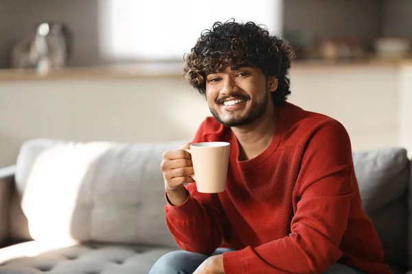 Evdeki Kanepede Bir Fincan Kahveyle Dinlenen Gülümseyen Yakışıklı Hintli Adam — Stok fotoğraf
