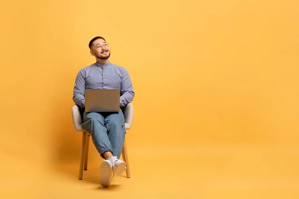 Portrét Zasněný Usmívající Asijský Muž Notebookem Sedí Křesle Dívá Nahoru — Stock fotografie