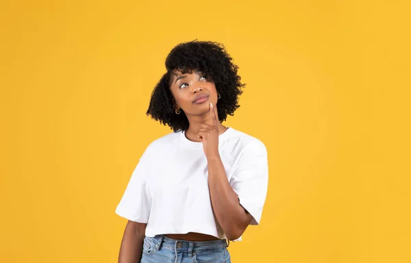 沉思积极的千年黑人女士穿休闲装 思考问题 看看孤立在橙色工作室背景下的复制空间 人类情感 创造解决方案 广告和提供 — 图库照片
