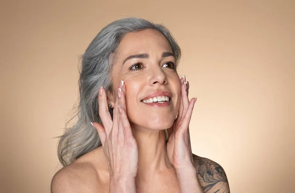 Mulher Sênior Bonita Tocando Sua Pele Rosto Liso Aplicando Creme — Fotografia de Stock