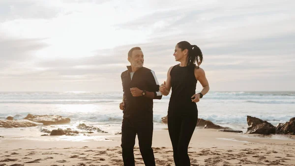 愉快的资深高加索人家庭在运动服慢跑 享受训练和积极的生活方式在海滩上 在早晨 一起照顾身体 — 图库照片