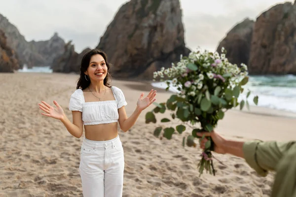 男与え花束の花へ驚き若い女性 ボーイフレンドはガールフレンドに会い 中に贈り物を与えます日付オンビーチ 海岸線の景色 — ストック写真